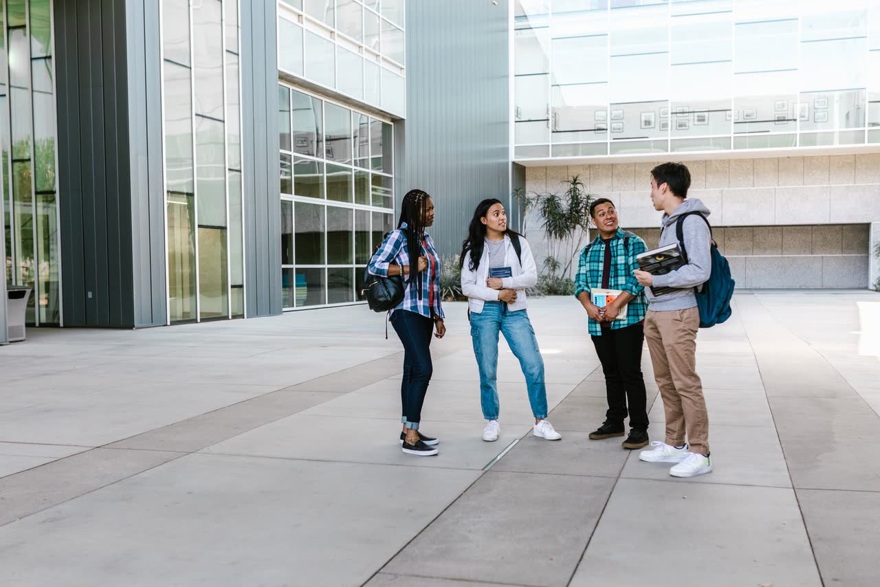 A diverse group of university students talking outside a modern campus